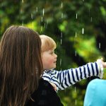 Child under the drops of summer rain