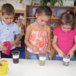Three children study the properties of sand, earth and clay